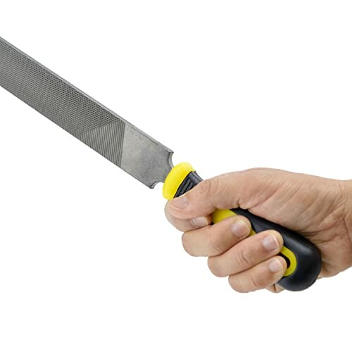 Hand holding a metal file with a yellow and black handle.